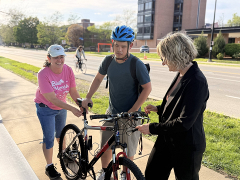 Two volunteers put bike lights on a students bike