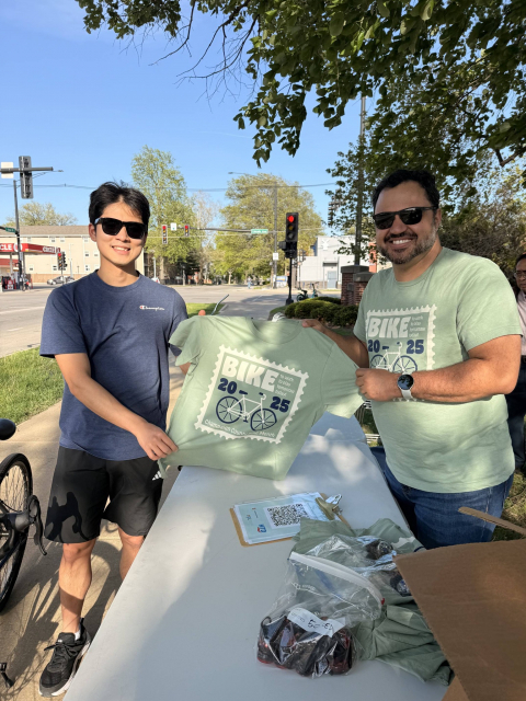 A volunteer and student hold up a Bike-to-Work Day 2025 t-shirt