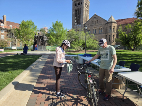 A volunteer helps a student put bike lights onto their bicycle.