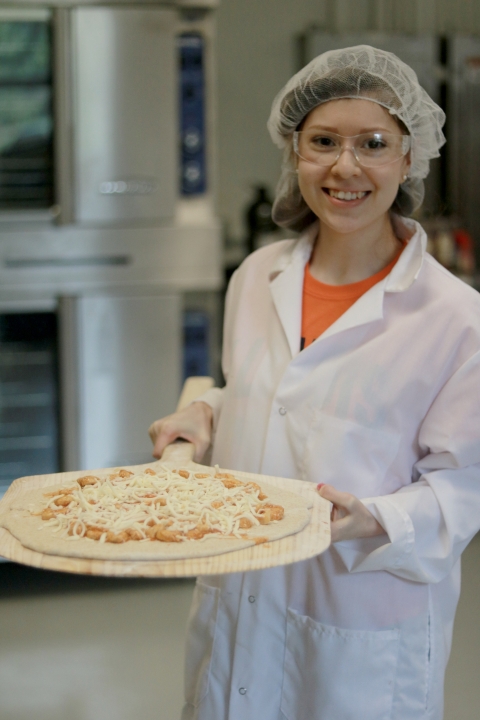 Individual poses with pizza made from project's tomato sauce.