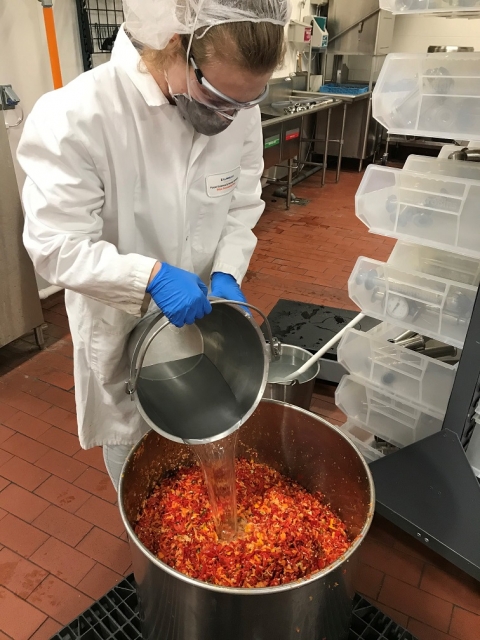 An individual creating wing sauce from peppers.
