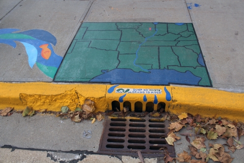 A map of the midwest painted above a storm drain which reads "Dump No waste, Draws To River"