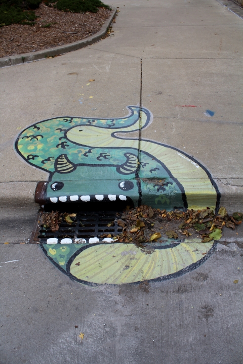 A mural slug-like creature with horns and a storm drain as its mouth