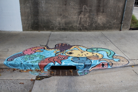 A mural of aquatic animals coming out of a storm drain near the Illinois Terminal