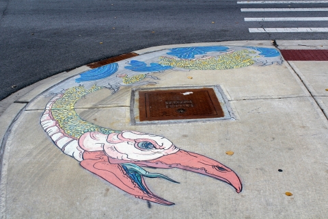 A mural of a creature with a yellow/pink snake-like body and a pelican-like head in waves of water