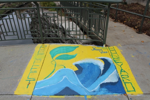 A mural of blue ocean waves and a green plant leaf on a yellow background. The word "Respect" is on the left edge of the yellow background, and the word "Boneyard" is the right edge of the yellow background.