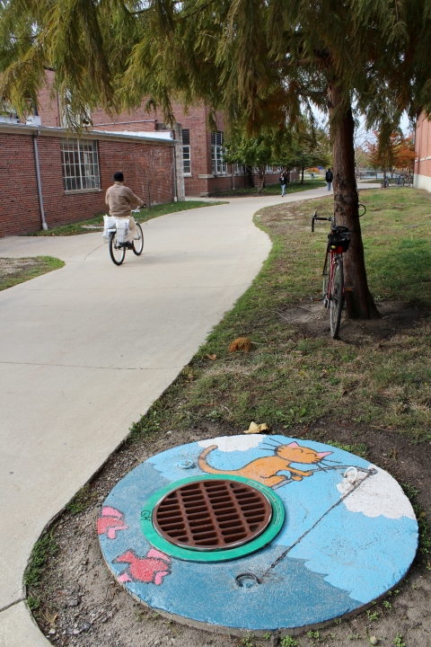 This picture shows the mural of the cat fishing is located next to a walkway near the Engineering Quad