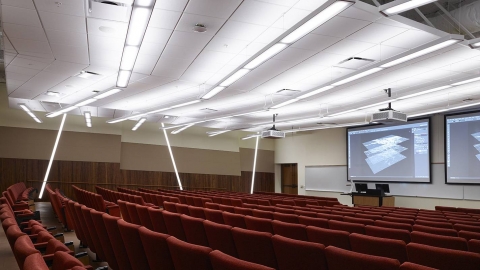 A lecture hall with a podium at the front and two projection screens.