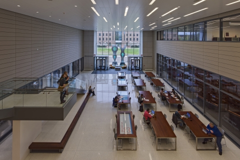 Overlook of the lobby from a mezzanine with students working at large tables.