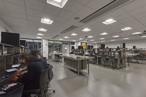 Students working on circuit boards in a laboratory with tables lined with computers.